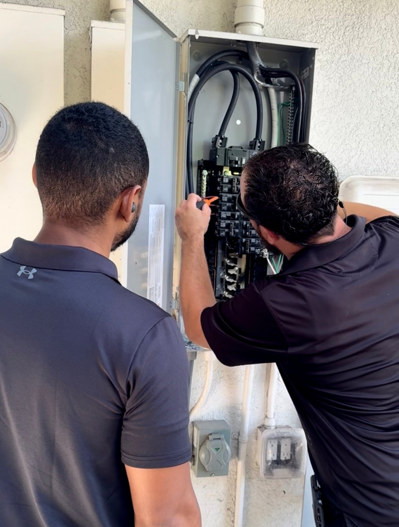 Two men working on electrical panel Two men working on electrical panel